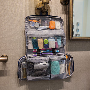 Organized travel hygiene essentials in a clean pouch with family travel scene in background - BBPOW family travel preparation
